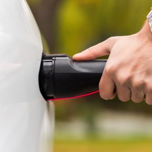 Close view of a man plugging charger into an electric car charging port